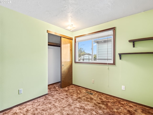 unfurnished bedroom featuring a closet, light carpet, and a textured ceiling