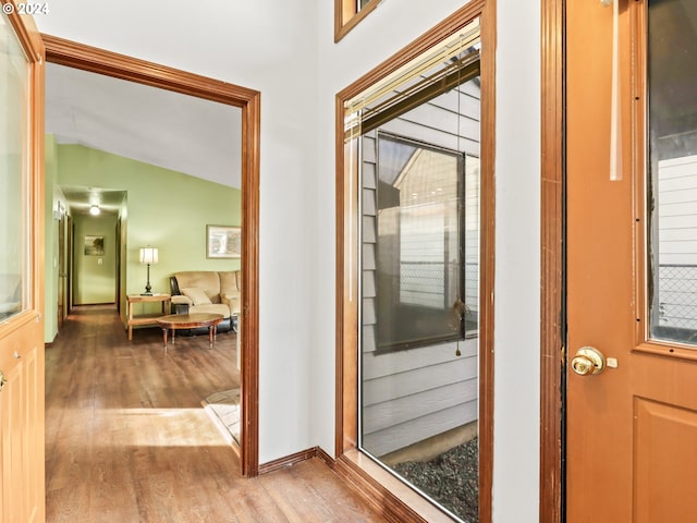 doorway to outside with vaulted ceiling and light wood-type flooring