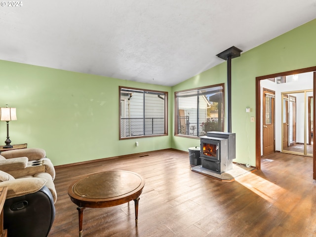 living room featuring a wood stove, hardwood / wood-style flooring, and vaulted ceiling