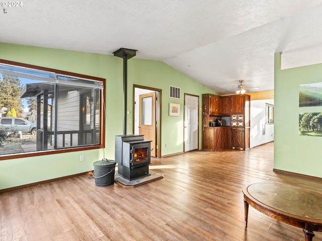 living room with lofted ceiling, ceiling fan, light hardwood / wood-style floors, and a wood stove