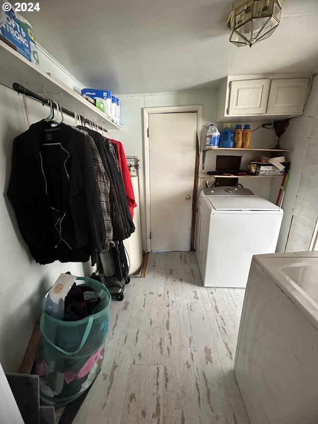 clothes washing area with cabinets, light wood-type flooring, and separate washer and dryer