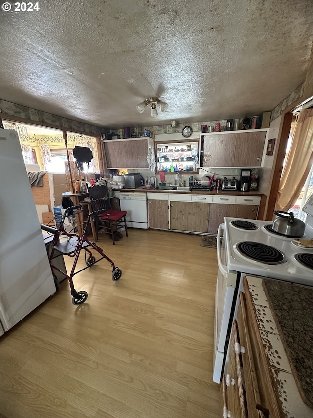 kitchen with ceiling fan, sink, a textured ceiling, white appliances, and light wood-type flooring