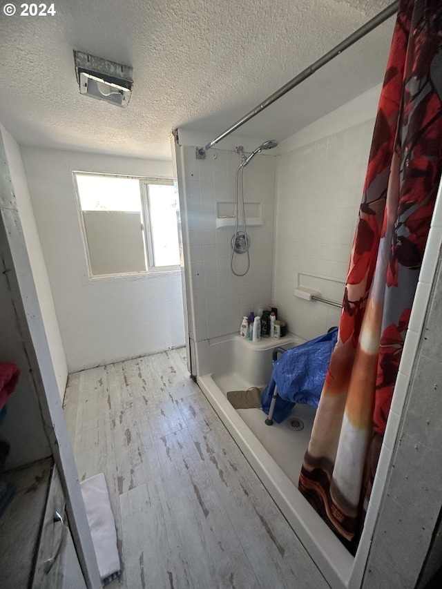 bathroom with hardwood / wood-style floors, a textured ceiling, and walk in shower