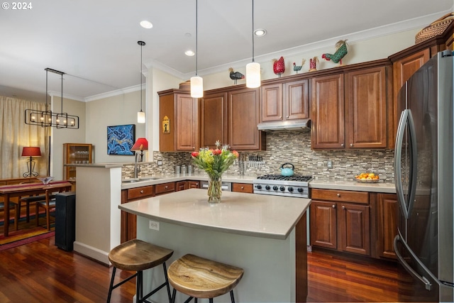 kitchen featuring pendant lighting, decorative backsplash, a kitchen island, a breakfast bar area, and stainless steel refrigerator