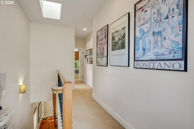 hallway with a skylight and light carpet