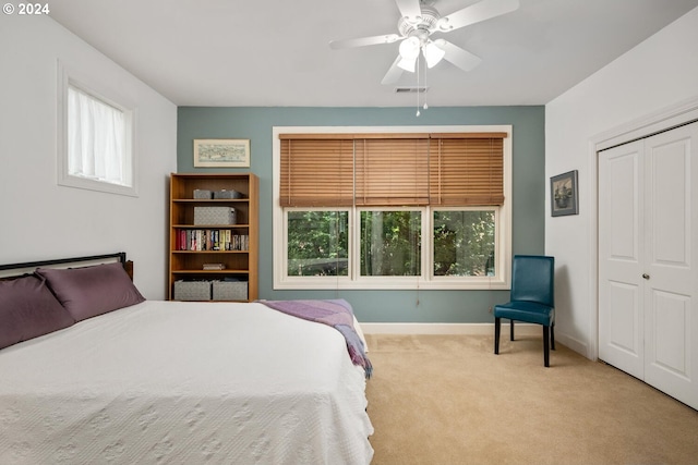 bedroom with light colored carpet, ceiling fan, and a closet