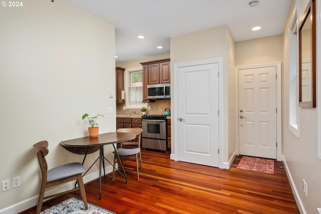 kitchen featuring stainless steel appliances, dark hardwood / wood-style flooring, and backsplash