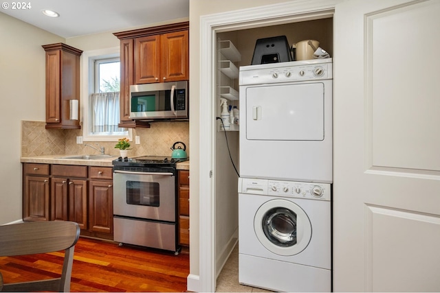 laundry room with sink, stacked washing maching and dryer, and dark hardwood / wood-style floors