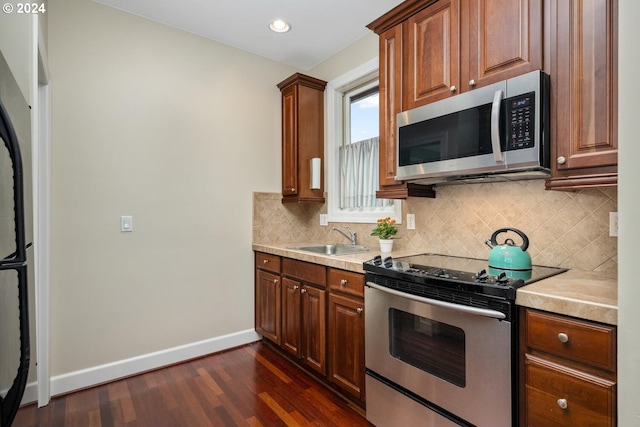 kitchen featuring sink, dark wood-type flooring, backsplash, and appliances with stainless steel finishes