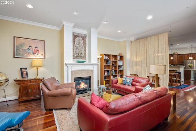 living room featuring dark hardwood / wood-style flooring, a tile fireplace, and crown molding