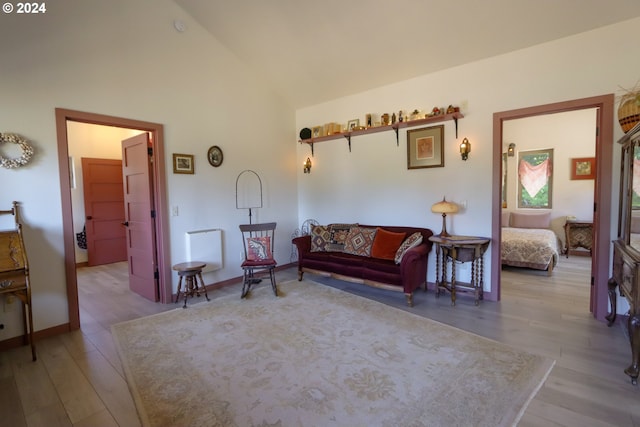 living area with high vaulted ceiling and light hardwood / wood-style flooring