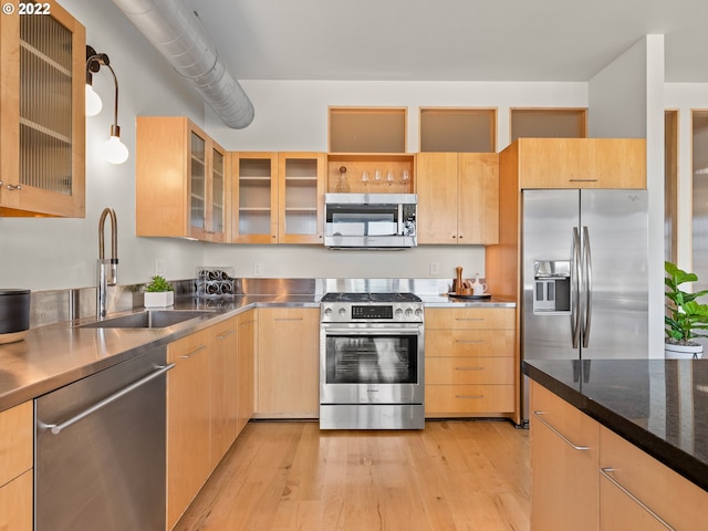 kitchen featuring stainless steel appliances, sink, light brown cabinets, and decorative light fixtures