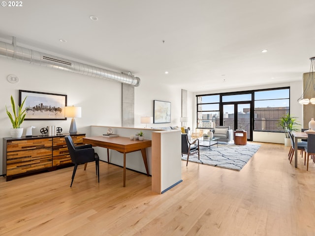 office area with floor to ceiling windows and light hardwood / wood-style flooring