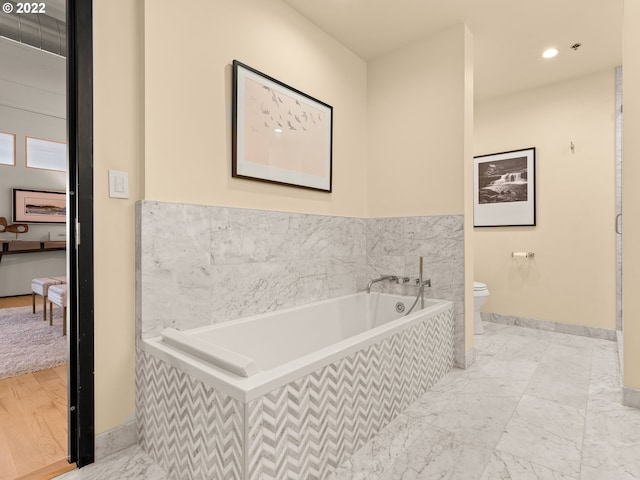 bathroom featuring toilet and tiled bath