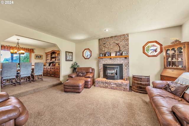 carpeted living room featuring an inviting chandelier, a textured ceiling, brick wall, and a brick fireplace