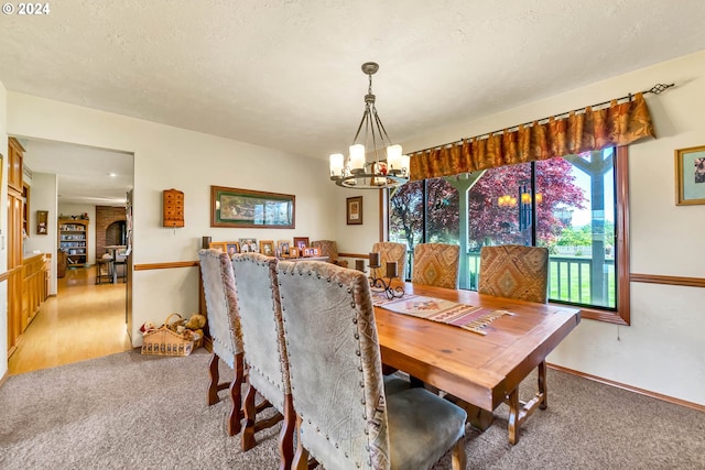 carpeted dining room with a textured ceiling and a chandelier