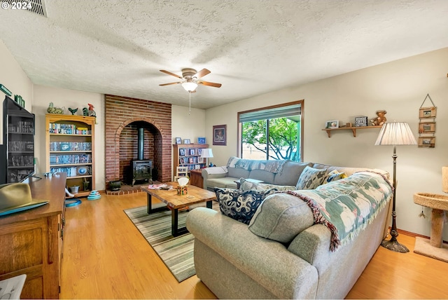 living room featuring a textured ceiling, brick wall, a wood stove, and wood-type flooring