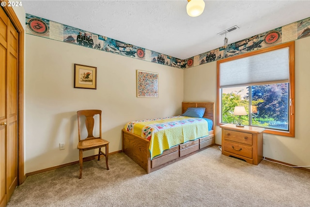 carpeted bedroom with a textured ceiling and a closet