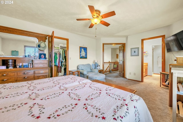 bedroom with a closet, connected bathroom, a spacious closet, carpet flooring, and ceiling fan