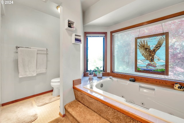 bathroom with tile floors, tiled tub, and toilet