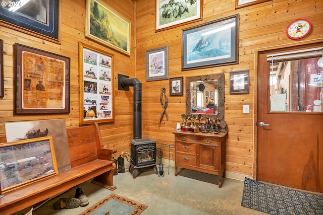 misc room with wooden walls, concrete floors, and a wood stove