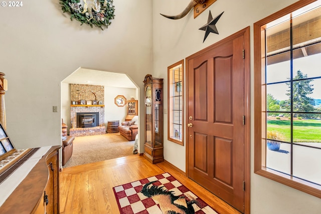 entryway with light hardwood / wood-style floors, a fireplace, and brick wall