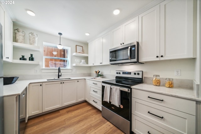 kitchen featuring white cabinets, decorative light fixtures, sink, and appliances with stainless steel finishes