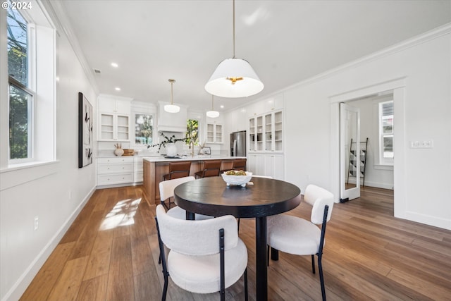 dining area with wood-type flooring and ornamental molding