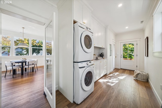 washroom with stacked washer / drying machine, dark hardwood / wood-style floors, a healthy amount of sunlight, and ornamental molding