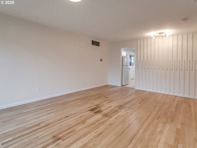 unfurnished room featuring baseboards, visible vents, and light wood finished floors