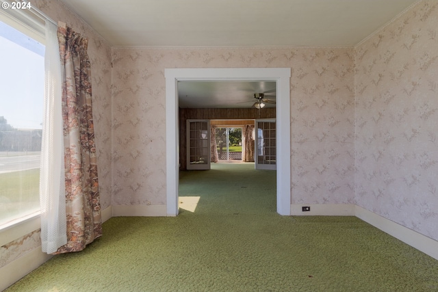 carpeted empty room with ceiling fan, plenty of natural light, and ornamental molding