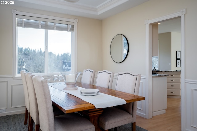 dining room featuring light hardwood / wood-style floors, crown molding, plenty of natural light, and a tray ceiling