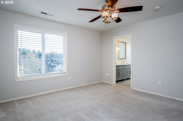 unfurnished bedroom with ensuite bathroom, light colored carpet, ceiling fan, and sink