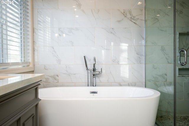 bathroom featuring tile walls, independent shower and bath, and vanity