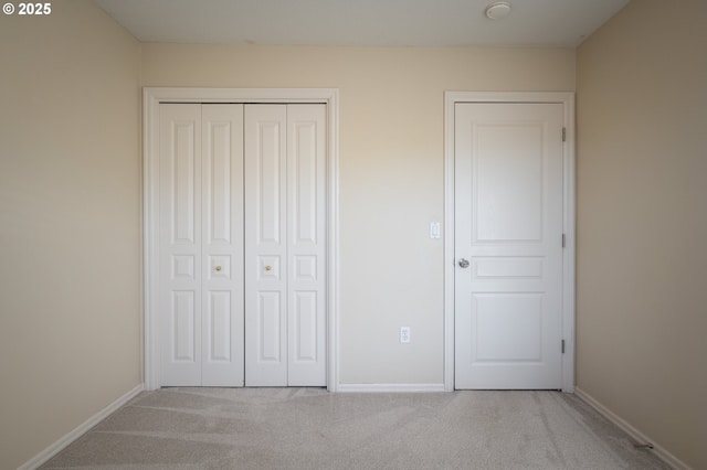 unfurnished bedroom featuring light colored carpet and a closet