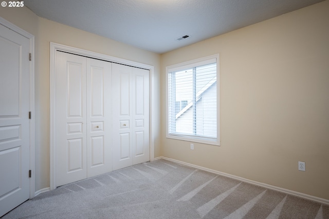 unfurnished bedroom with a closet and light carpet