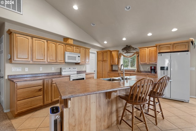 kitchen featuring lofted ceiling, white appliances, sink, light tile patterned flooring, and a center island with sink