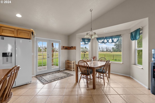 dining area with a notable chandelier, vaulted ceiling, light tile patterned floors, and french doors