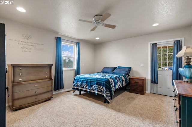 bedroom featuring ceiling fan, light colored carpet, and a textured ceiling