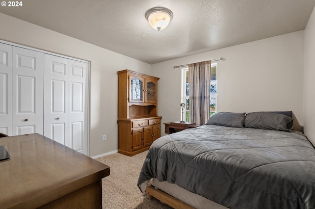 carpeted bedroom with a textured ceiling and a closet