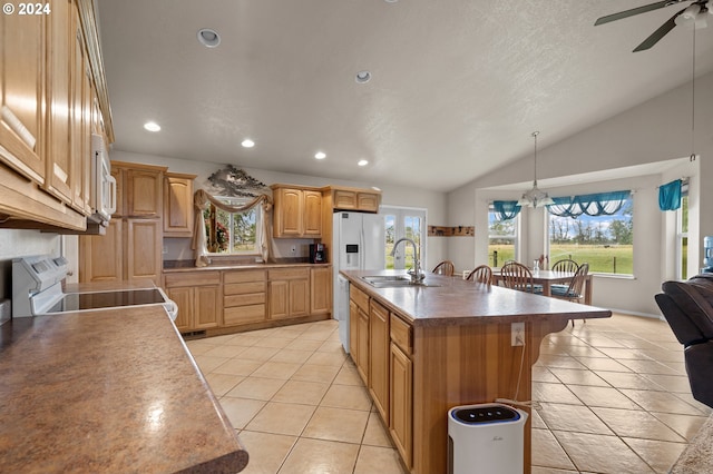 kitchen with lofted ceiling, hanging light fixtures, sink, white appliances, and a kitchen island with sink