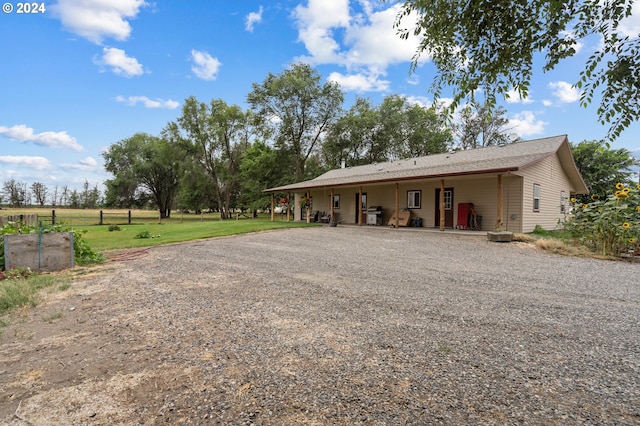 back of property with a yard and covered porch