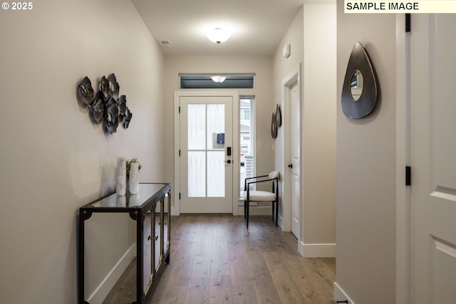 doorway to outside with light wood finished floors, visible vents, and baseboards