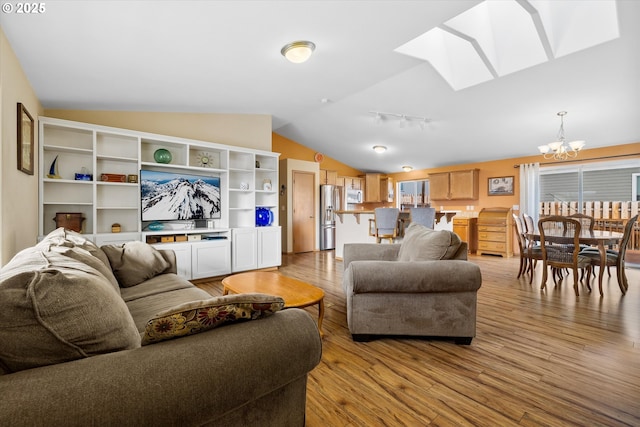 living room featuring vaulted ceiling, light wood-type flooring, and a chandelier