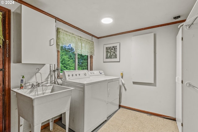 clothes washing area with crown molding, sink, and washer and dryer