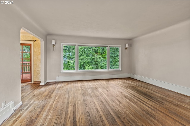 unfurnished room with light wood-type flooring and a baseboard heating unit