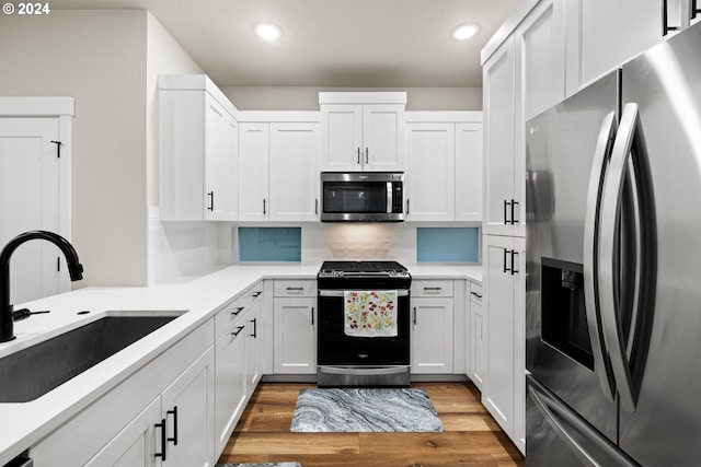 kitchen featuring appliances with stainless steel finishes, white cabinets, sink, and light hardwood / wood-style floors