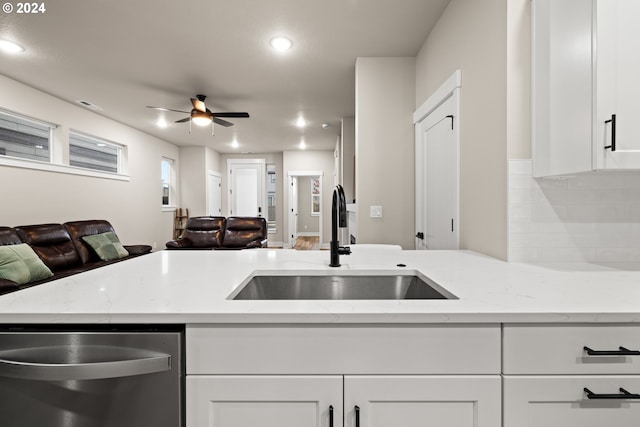 kitchen with sink, dishwasher, ceiling fan, white cabinets, and light stone counters