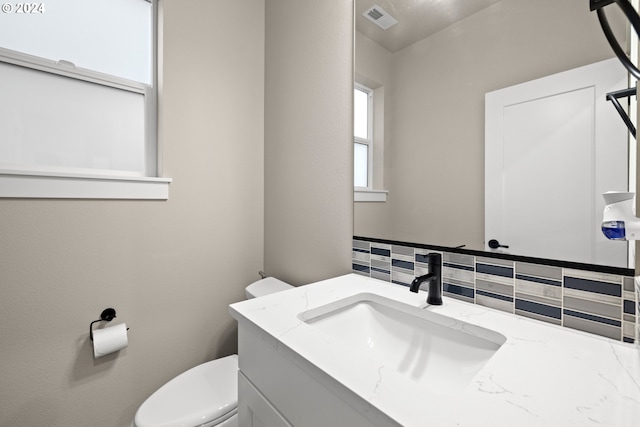 bathroom featuring backsplash, vanity, and toilet