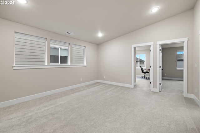 carpeted empty room with lofted ceiling